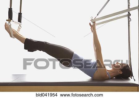 Picture - Woman stretching on exercise equipment. Fotosearch