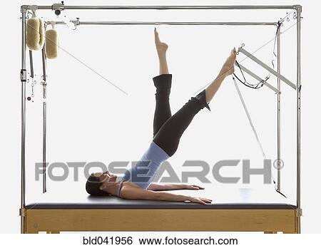 Stock Image - Woman stretching on exercise equipment. Fotosearch - Search Stock Photography, Poster Photos, Pictures, and Photo Clip Art