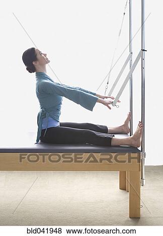 Stock Photo - Woman stretching on exercise equipment. Fotosearch