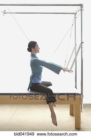 Stock Photo - Woman stretching on exercise equipment. Fotosearch