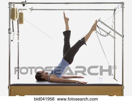 Stock Photograph - Woman stretching on exercise equipment. Fotosearch