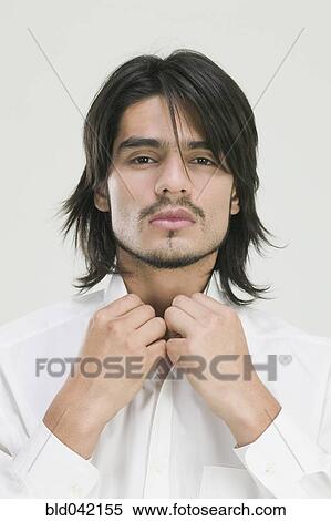 Stock Photography - Young Hispanic man buttoning shirt. Fotosearch