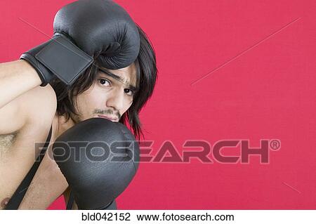 Stock Image - Young Hispanic man wearing boxing gloves. Fotosearch