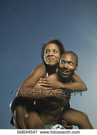 Stock Photo - African American man giving girlfriend piggyback ride. Fotosearch