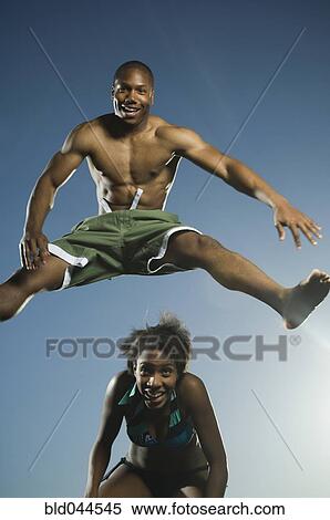 Stock Photography - African American man in bathing suit jumping over woman. Fotosearch