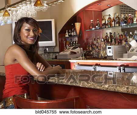 Stock Photography - African American woman sitting at bar. Fotosearch