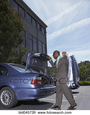 Stock Photo - African businessman holding dry cleaning. Fotosearch