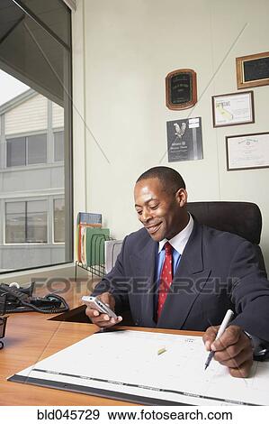 African businessman looking at electronic organizer View Large Photo Image Stock Photo - African businessman looking at electronic organizer. Fotosearch