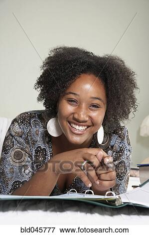Stock Photo - African woman studying on bed. Fotosearch