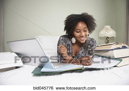 African woman studying on bed View Large Photo Image Stock Photograph - African woman studying on bed. Fotosearch