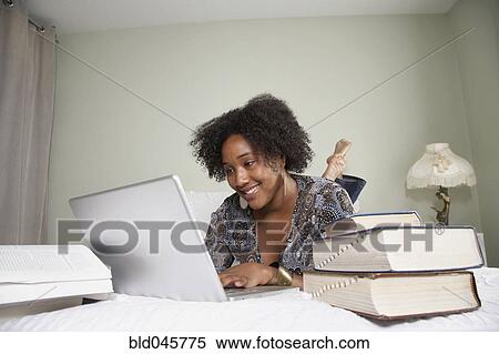Stock Photography - African woman studying on bed. Fotosearch