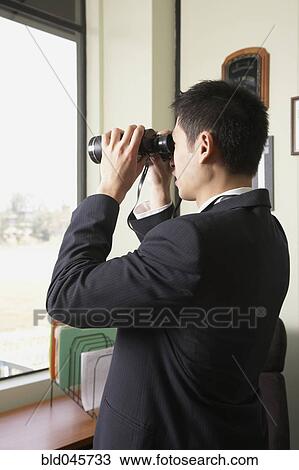 Stock Image - Asian businessman looking through binoculars. Fotosearch