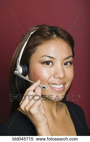 Stock Photography - Asian businesswoman wearing headset. Fotosearch
