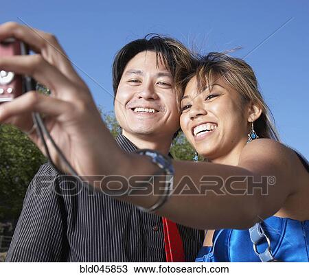 Stock Image - Asian couple taking own photograph. Fotosearch