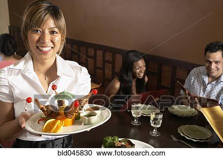 Asian female server holding plate of food View Large Photo Image Stock Image - Asian female server holding plate of food. Fotosearch