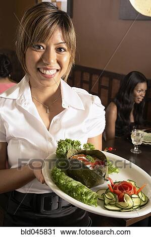 Asian female server holding plate of food View Large Photo Image Stock Image - Asian female server holding plate of food. Fotosearch