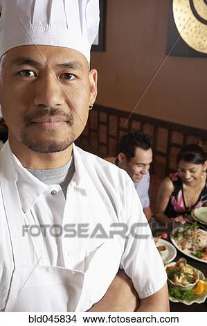 Picture - Asian male chef with diners in background. Fotosearch