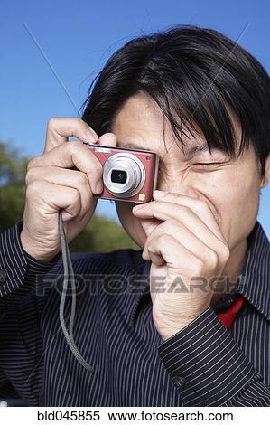 Stock Photography - Asian man taking photograph. Fotosearch