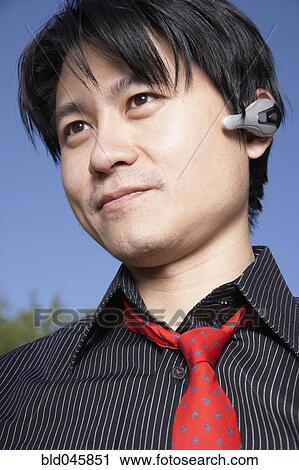 Stock Image - Asian man using hands free device. Fotosearch