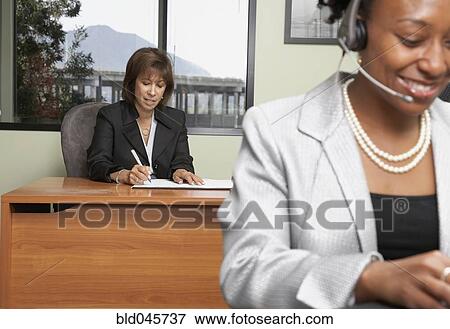 Stock Photo - Businesswoman writing at desk. Fotosearch