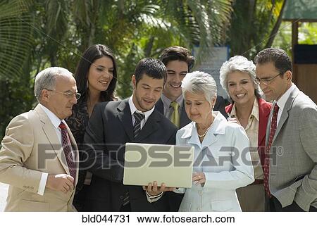 Stock Image - Group of Hispanic businesspeople looking at laptop. Fotosearch