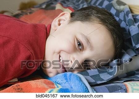 Stock Photo - Hispanic boy laying in bed. Fotosearch