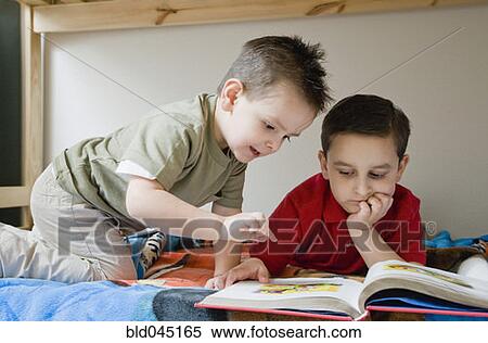 Stock Photography - Hispanic brothers reading book. Fotosearch