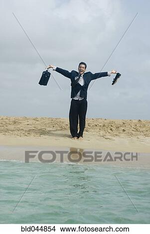 Picture - Hispanic businessman at beach. Fotosearch
