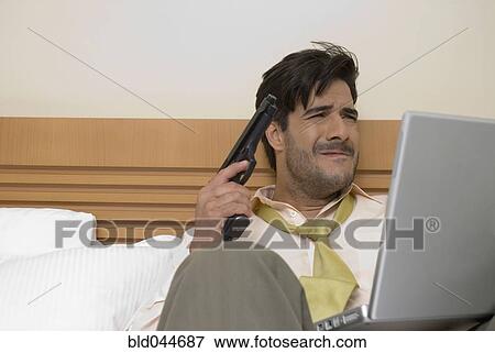 Stock Photo - Hispanic businessman holding gun and laptop. Fotosearch