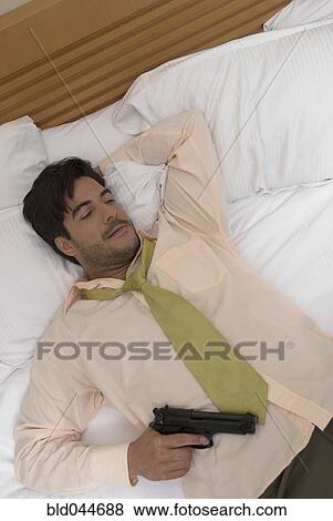 Hispanic businessman holding gun in bed View Large Photo Image Stock Photo - Hispanic businessman holding gun in bed. Fotosearch