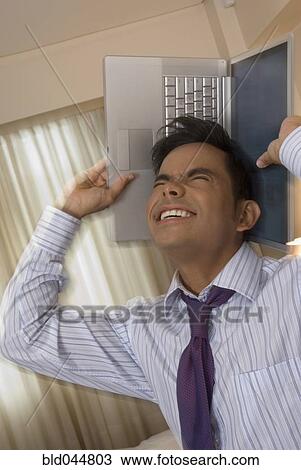 Hispanic businessman holding laptop around head View Large Photo Image Stock Image - Hispanic businessman holding laptop around head. Fotosearch