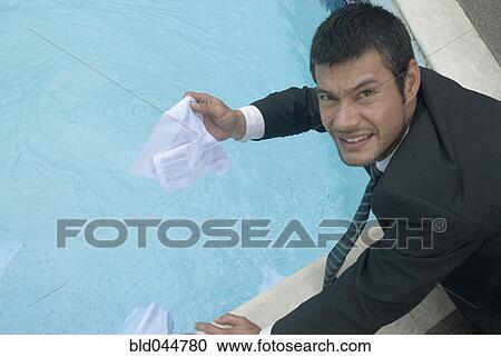 Stock Image - Hispanic businessman holding wet paperwork. Fotosearch