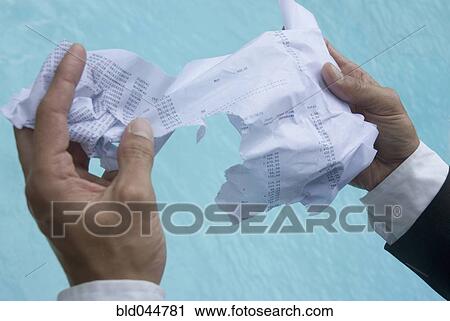 Stock Image - Hispanic businessman holding wet paperwork. Fotosearch