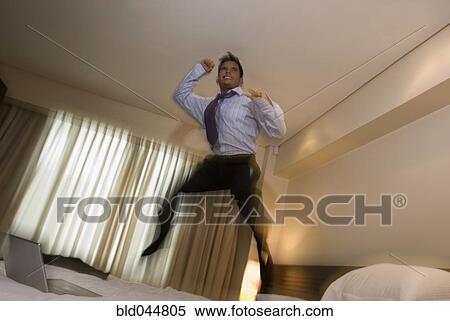 Hispanic businessman jumping on bed View Large Photo Image Stock Photography - Hispanic businessman jumping on bed. Fotosearch