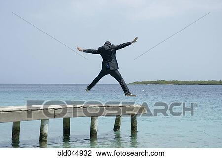 Hispanic businessman jumping on dock View Large Photo Image Stock Image - Hispanic businessman jumping on dock. Fotosearch