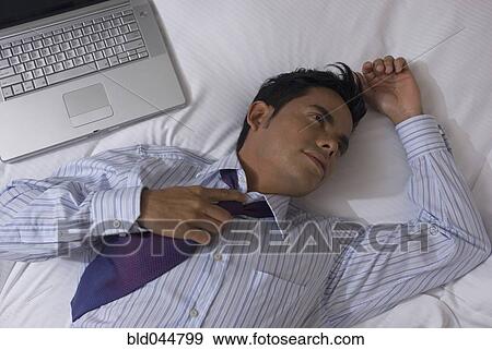 Stock Photo - Hispanic businessman laying on bed. Fotosearch