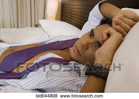 Stock Photo - Hispanic businessman laying on bed. Fotosearch
