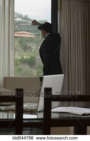 Stock Photo - Hispanic businessman looking out window. Fotosearch