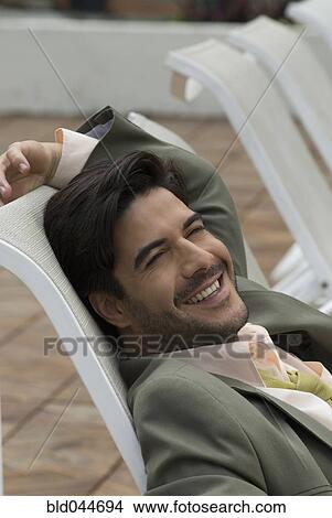 Picture - Hispanic businessman sitting in lounge chair. Fotosearch