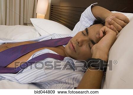 Hispanic businessman sleeping on bed View Large Photo Image Stock Photo - Hispanic businessman sleeping on bed. Fotosearch
