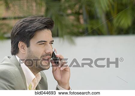 Stock Image - Hispanic businessman talking on cell phone. Fotosearch