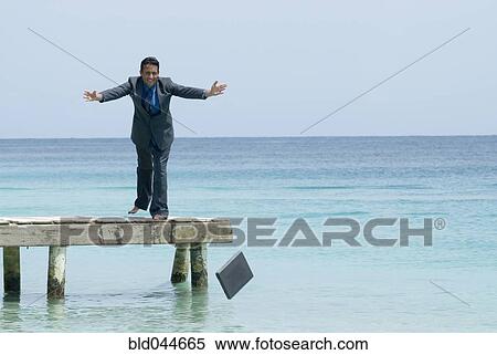 Stock Photography - Hispanic businessman throwing laptop into water. Fotosearch