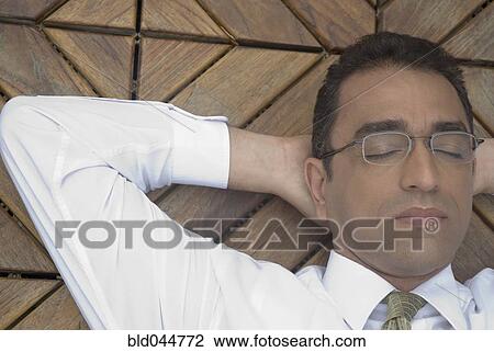 Stock Image - Hispanic businessman with hands behind head. Fotosearch