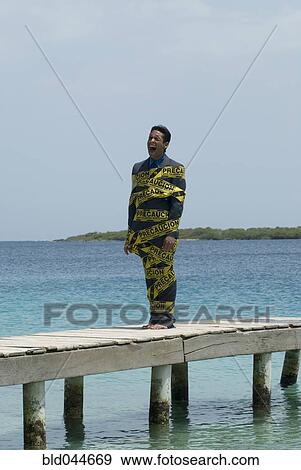 Hispanic businessman wrapped in Caution tape View Large Photo Image Stock Photo - Hispanic businessman wrapped in Caution tape. Fotosearch