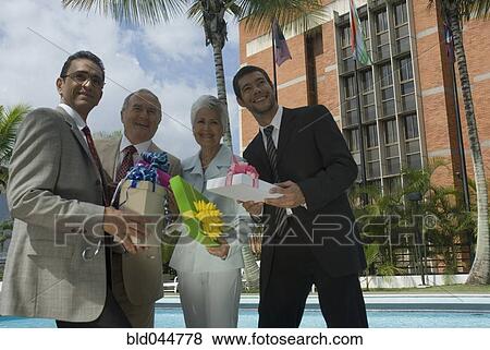Stock Photo - Hispanic businesspeople holding gifts. Fotosearch