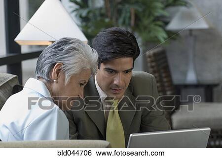 Stock Photograph - Hispanic businesspeople looking at laptop. Fotosearch