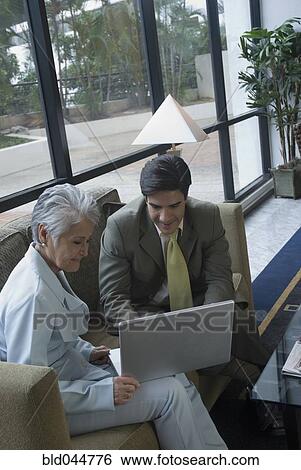 Hispanic businesspeople looking at laptop View Large Photo Image Stock Photograph - Hispanic businesspeople looking at laptop. Fotosearch