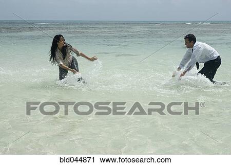 Stock Image - Hispanic businesspeople playing in water. Fotosearch