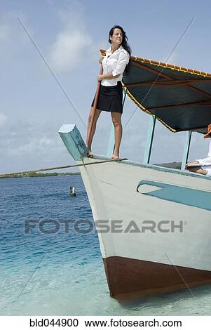 Stock Image - Hispanic businesswoman standing on boat. Fotosearch