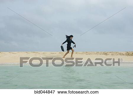 Stock Photo - Hispanic businesswoman walking on beach. Fotosearch
